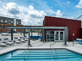 A pool area with a red building and a white building in the background.